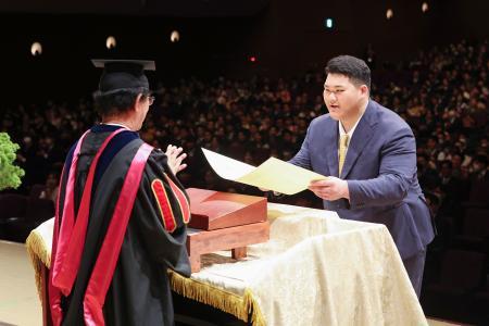 国士舘大の卒業式で、佐藤圭一学長から賞状を受け取る斉藤立＝２０日、横浜市（同大学提供）（共同）