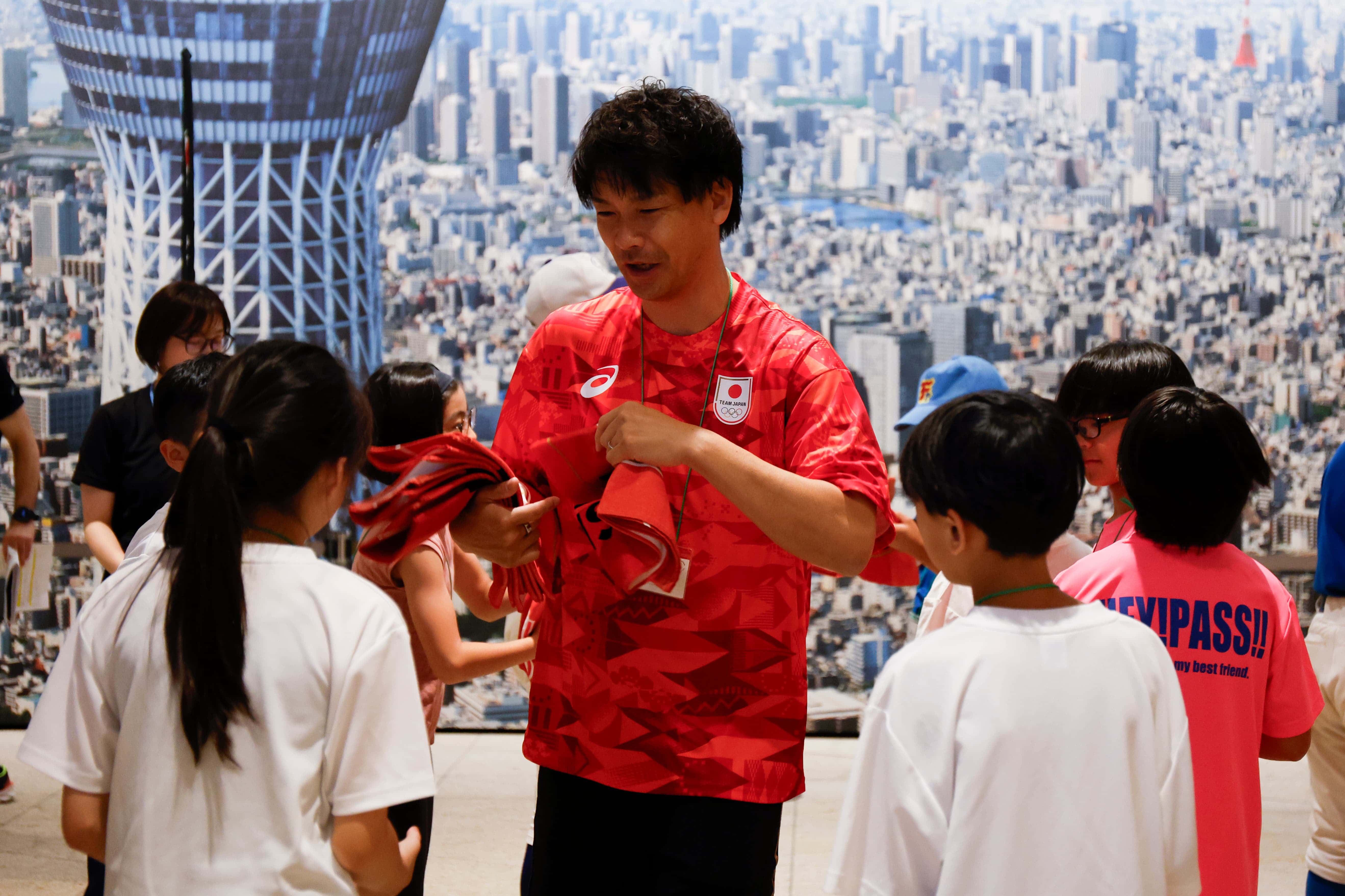 小学生にタオルをプレゼントする小口貴久さん（写真：フォート・キシモト）