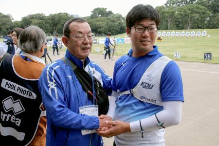 現役最後の試合を終え、近大の山田秀明監督（左）と握手するアーチェリー男子の古川高晴＝夢の島公園アーチェリー場（共同）