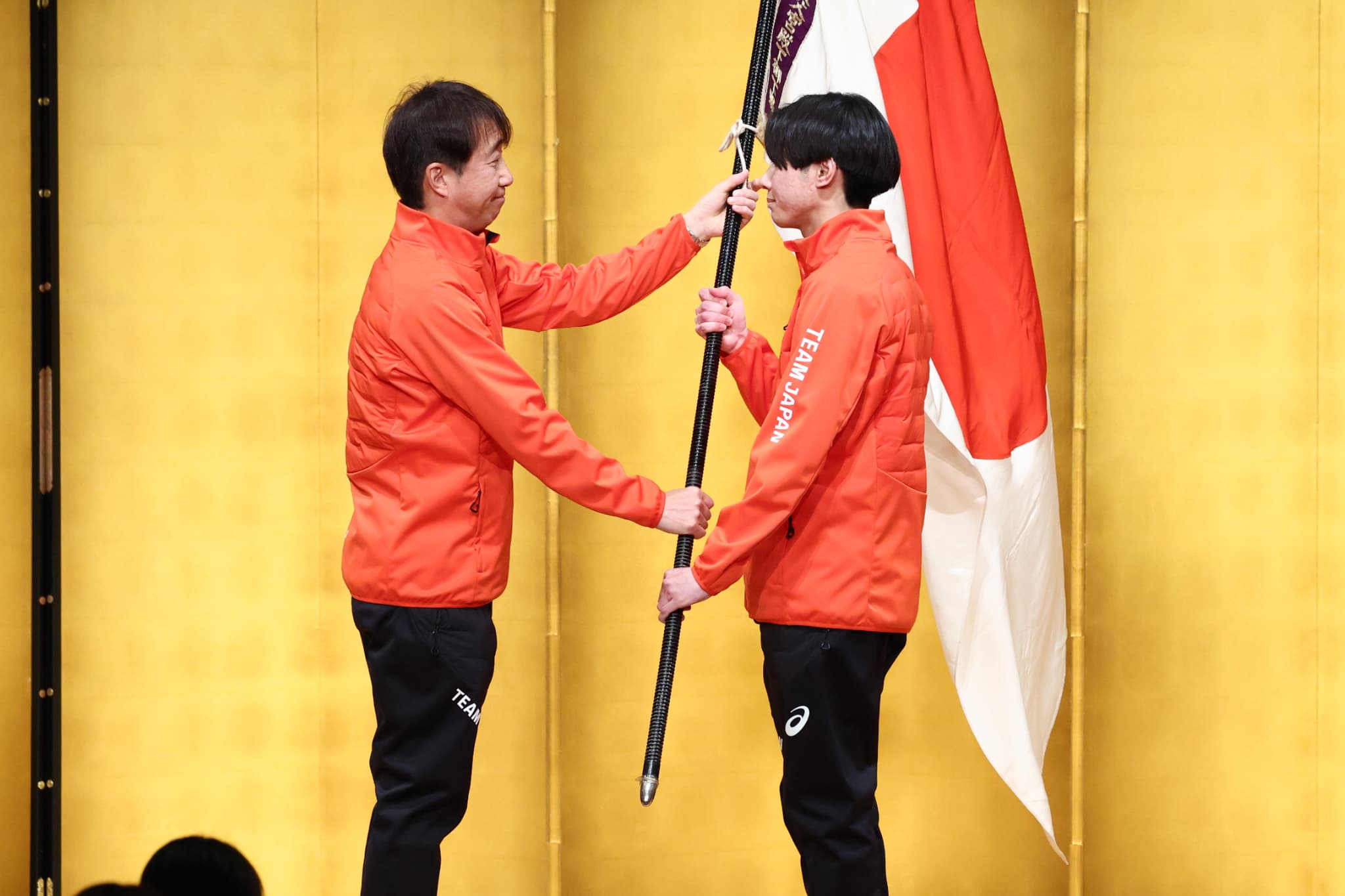 原田雅彦団長（左）から渡邊陽紀旗手へと団旗が授与された（写真：アフロスポーツ）